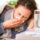 Woman with flu symptoms resting under a blanket